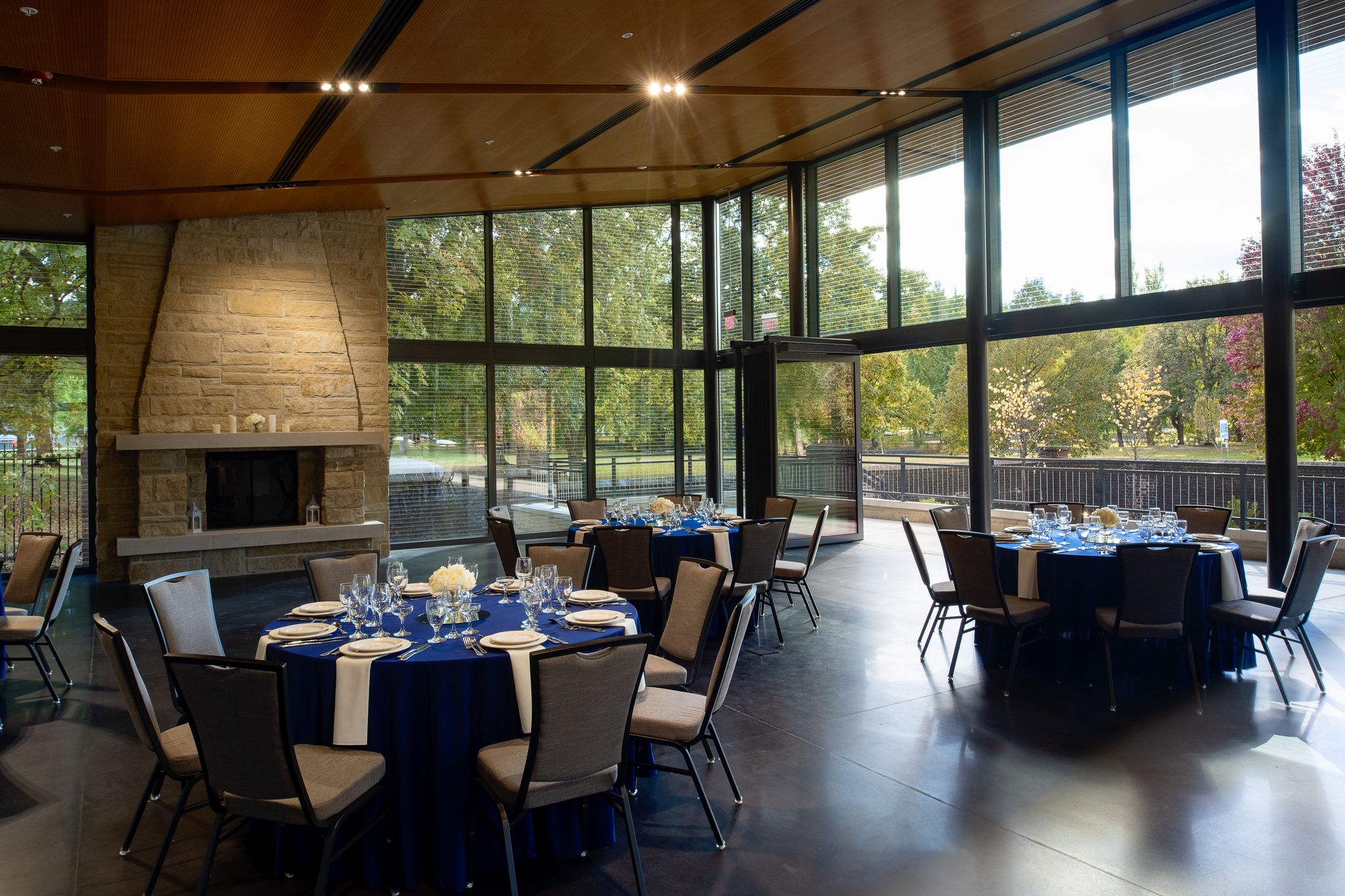 Three round event tables set up for an event in The Garden room with a fireplace in front of the open doors