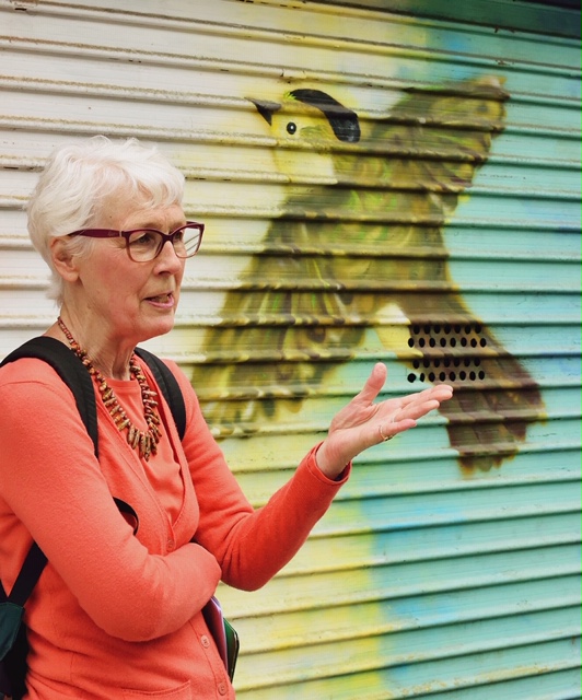 Leigh Hallingby in front of a mural with a bird