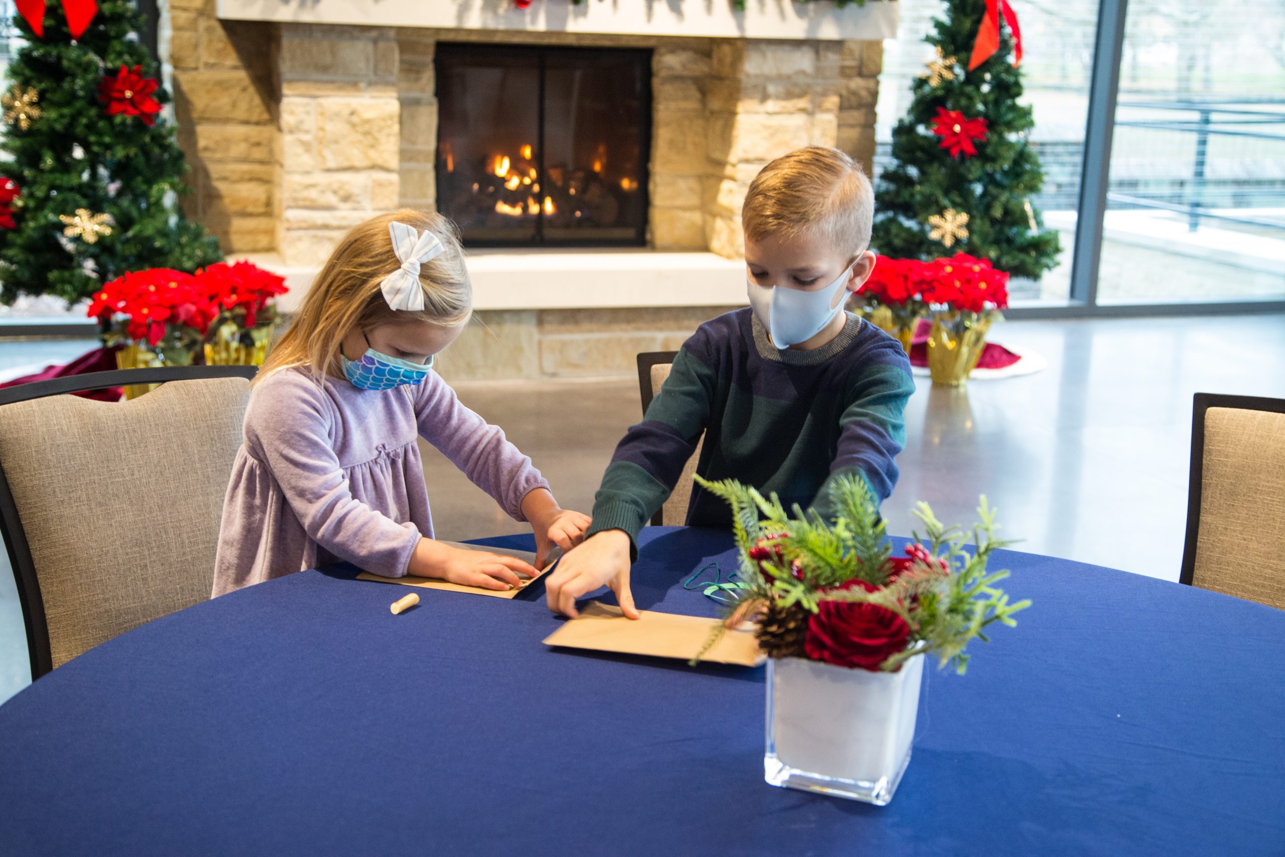 Two children working on craft in The Garden Room decorated for the holidays