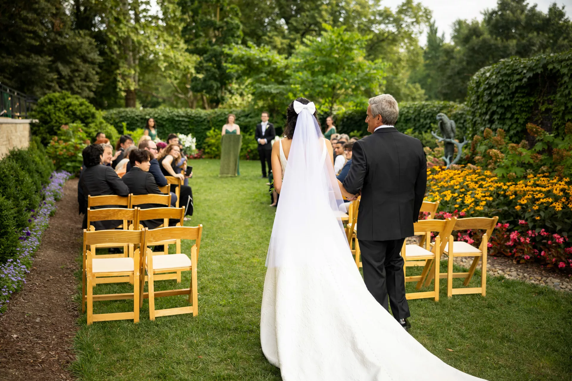 A dad walking his daughter down the isle at her wedding in the National Aviary's outdoor venue, The Garden Room.