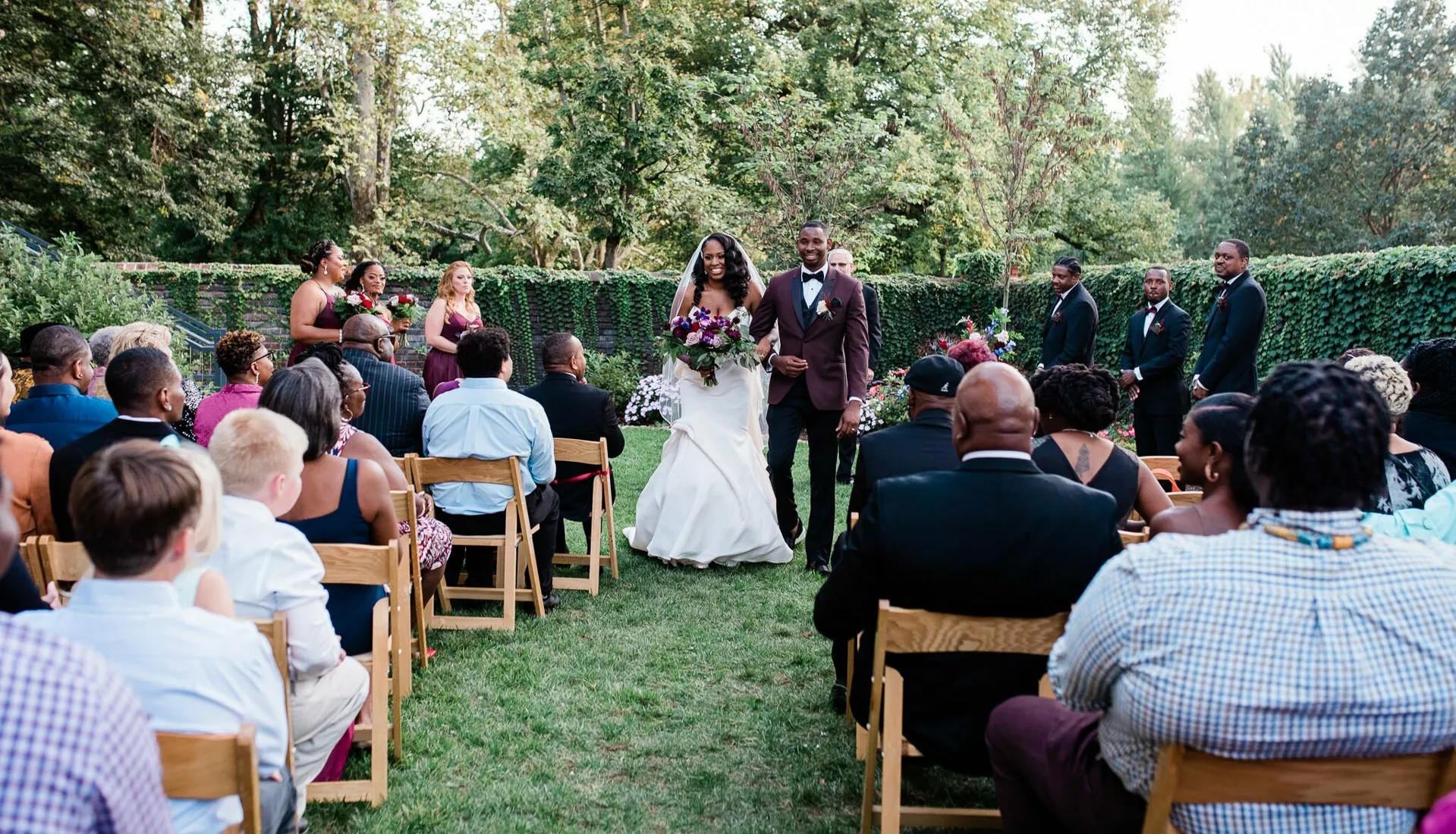 A just-married couple smiling while walking down the isle after their ceremony.