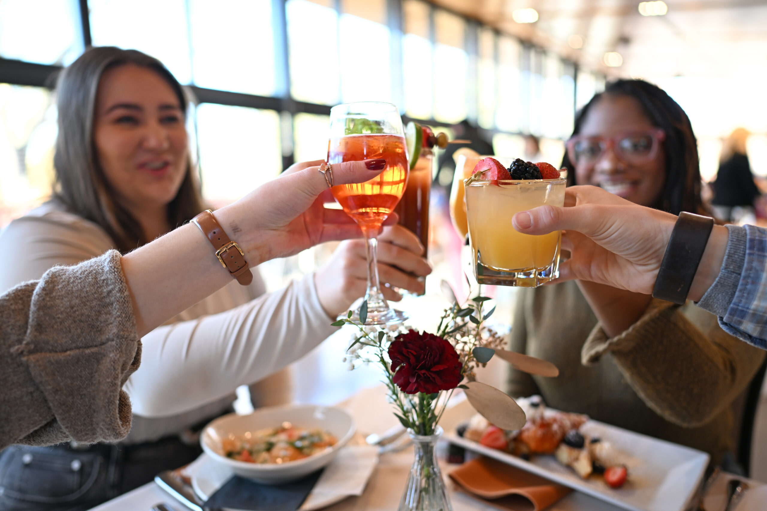 Four friends cheering their glasses at the National Aviary's Brunch in The Garden Room
