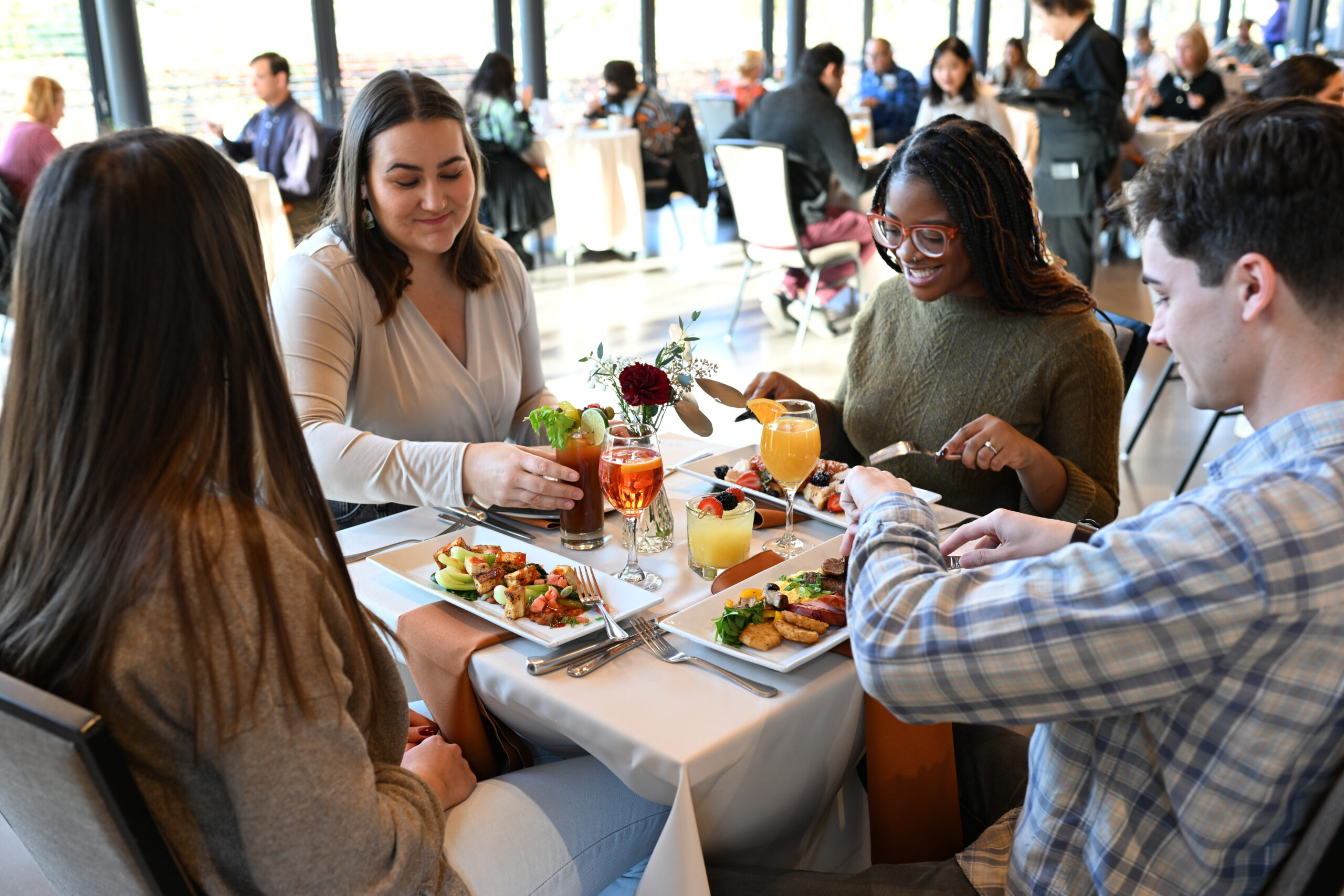 Four friends cheering their glasses at the National Aviary's Brunch in The Garden Room