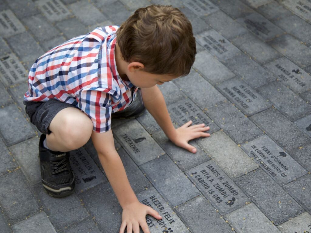A small boy kneeling and looking at pavers