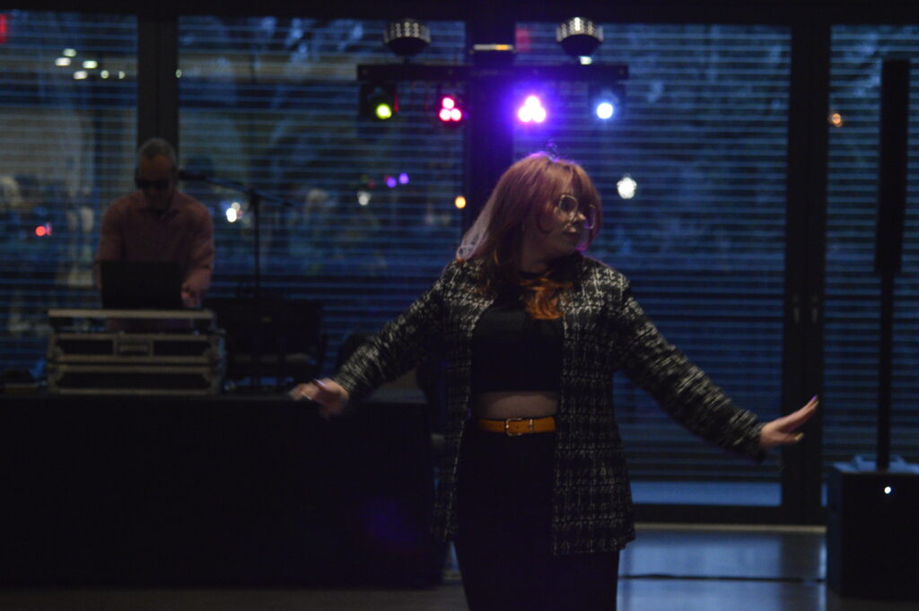 A girl dancing while a DJ spins tunes in the background