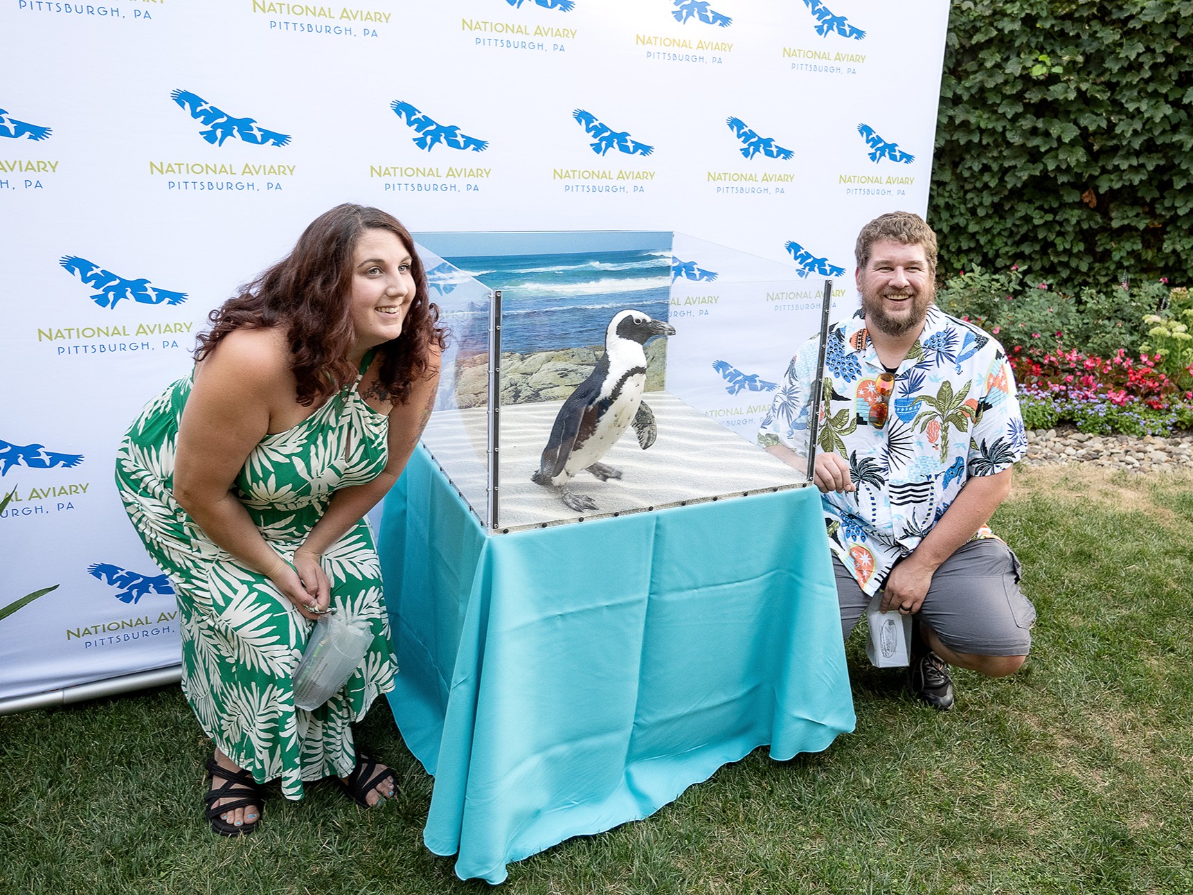 Two people posing for a photo with an African Penguin